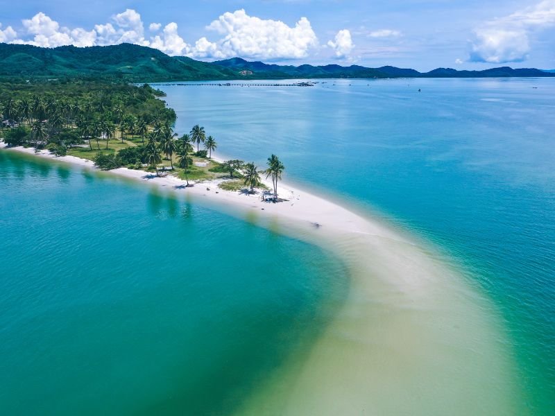 Dronebeeld van een smalle zandstrook met palmbomen die uitloopt in zee bij Koh Yao Yai, Thailand
