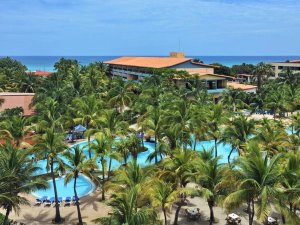 Luchtfoto van een tropisch resort met een kronkelend zwembad, palmbomen, gebouwen en de oceaan in Cuba