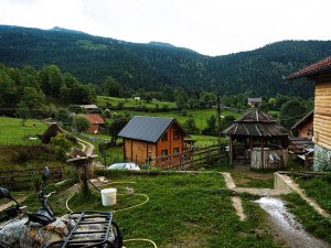 Landelijk landschap in Rugova in Kosovo met houten huizen, groene velden en bergen op de achtergrond
