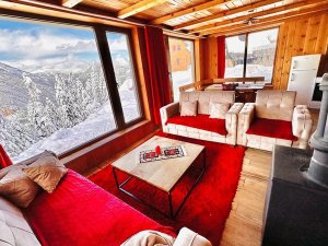 Gezellige woonkamer in een berghut in Kosovo met groot raam en uitzicht op besneeuwde bergen