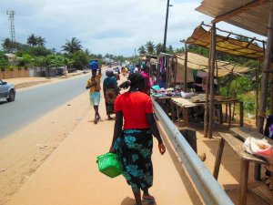 Vrouwen lopen langs een stoffige markt langs de weg, waarvan één een groene mand draagt in Zuid-Afrika