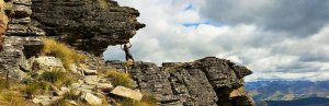 Persoon doet alsof hij een overhangende rots op een berg omhooghoudt in Nieuw-Zeeland