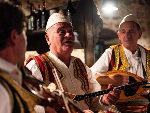 Drie Albanese muzikanten in traditionele kleding spelen viool, luit en bouzouki