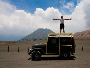 Vrouwelijke reiziger staand op een stoere 4x4 op het maanlandschap van de Bromo