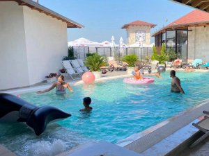 Gezinnen spelen in een zwembad met opblaasfiguren en ligbedden bij een hotel in Krujë in Albanië