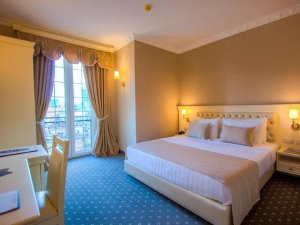 Klassieke hotelkamer met groot bed, warme kleuren en balkon met openslaande deuren in Tirana in Albanië
