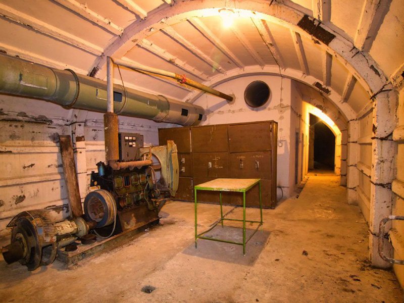Verlaten bunker in Albanië met betonnen bogen, een grote roestige generator, ventilatiebuizen, kasten en een donkere gang