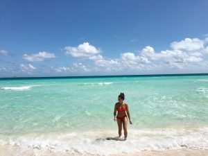 Vrouw in een rode bikini staat in helder turquoise zeewater in Cuba