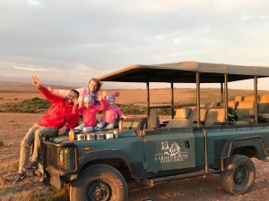 Lachend gezin van vier poseert op een safarivoertuig van Garden Route Game Lodge in Zuid-Afrika