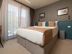 Moderne hotelkamer met groot bed, zachte tinten en grote ramen met gordijnen in Pristina in Kosovo
