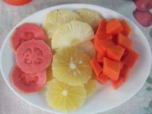 Wit bord met gesneden guave, ananas, citrus en papaja in Cuba