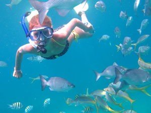 Persoon snorkelt onder water omringd door veel vissen in Cuba