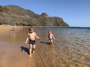Twee jonge jongens lachen op een zonnig strand op de Canarische Eilanden.