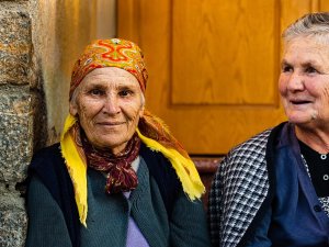 Twee oudere vrouwen in Ohrid in Noord-Macedonië die glimlachen, waarvan één met een kleurrijke hoofddoek recht in de camera kijkt