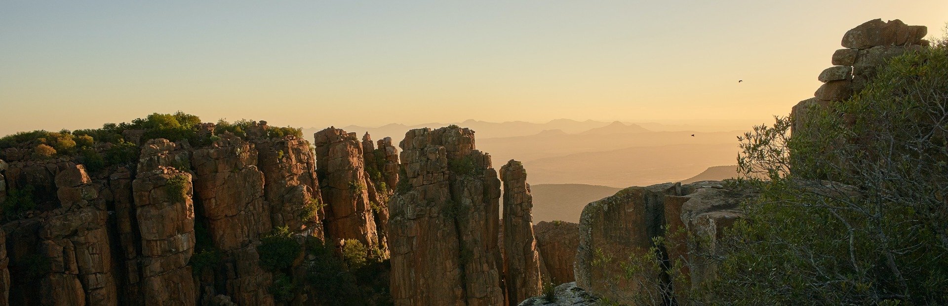 Panoramisch uitzicht op ruige rotsformaties bij zonsondergang met mistige bergen in de verte in Zuid-Afrika