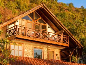 Rustiek huis in Albanië met rood pannendak, stenen gevel en houten balkon op een beboste heuvel