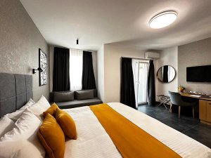 Moderne hotelkamer in Albanië met bed, gele kussens, bureau, tv en balkondeur