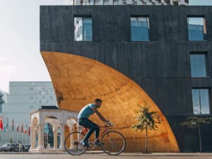 Man fietst langs een donker gebouw met een grote gebogen gouden wand in Tirana in Albanië