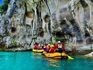 Mensen raften op helder turquoise water langs een hoge rotswand tijdens raften in Osum Canyon, Berat, Albanië