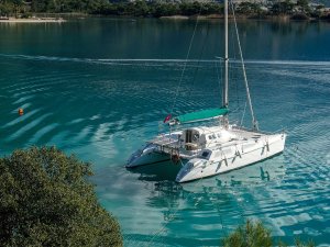 White catamaran sailboat on clear turquoise water.