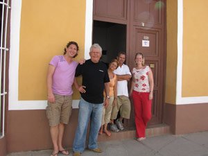 Vijf mensen poseren buiten een geelbruin gebouw in Cuba