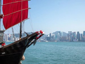 Traditionele zwarte jonkvrouwboot met rood zeil voor een moderne skyline aan het water in Australië