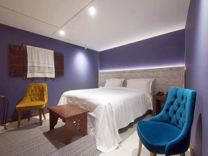 Moderne hotelkamer in Korçë in Albanië met groot bed, kleurrijke fauteuils en sfeervolle verlichting