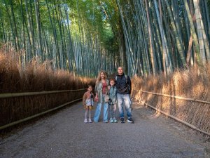 Een gezin staat samen op een rustig pad tussen hoge bamboestammen in Japan.