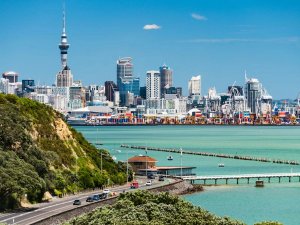 Stads skyline van Auckland met de Sky Tower, een haven met een drukke haven en een kustweg aan de kust in Nieuw-Zeeland