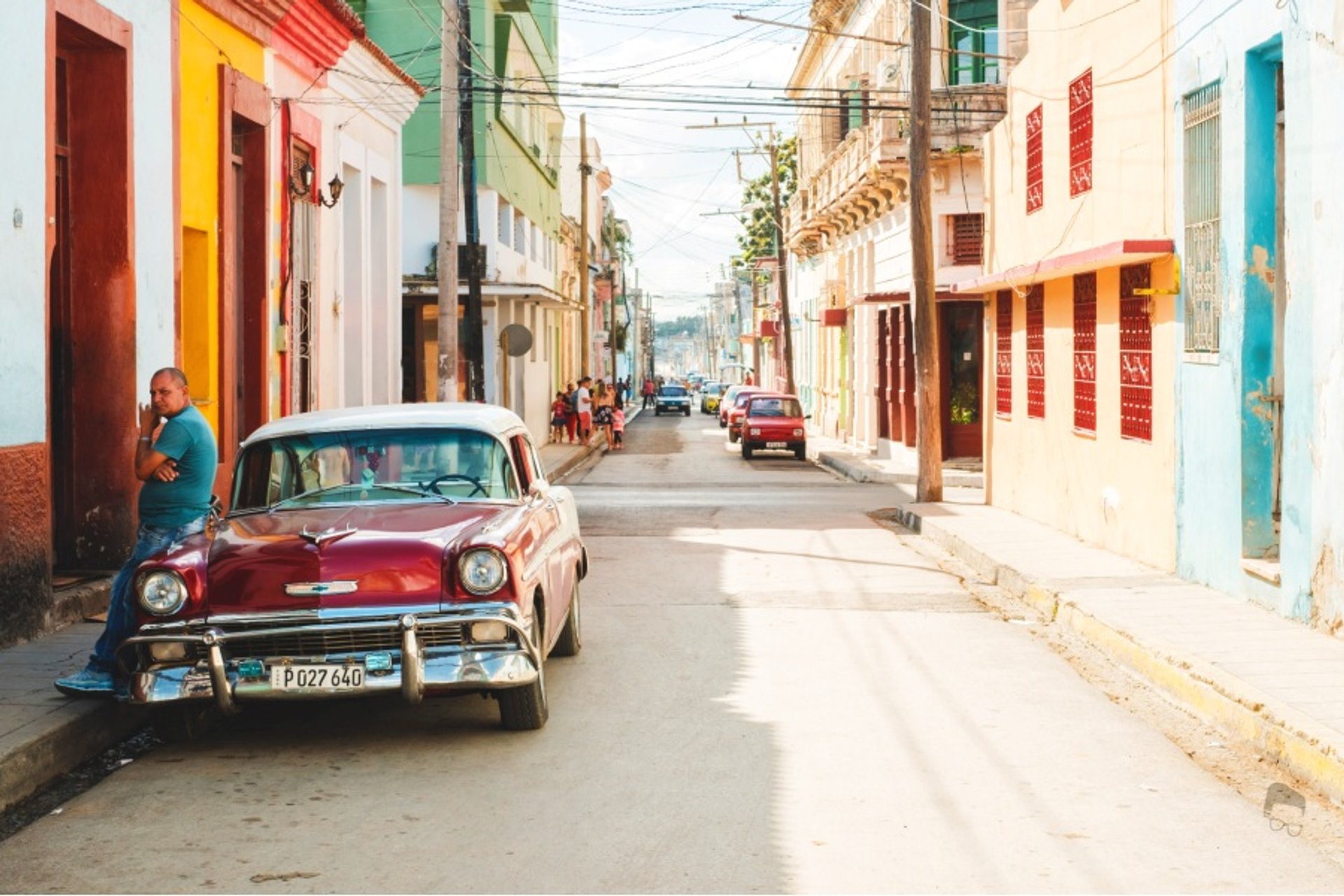 Rode klassieke auto en een man in een kleurrijke straat in Cuba met oude koloniale gebouwen