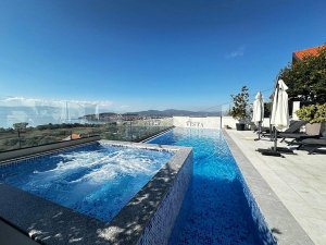 La Vista rooftop infinity pool in Albanië met jacuzzi en uitzicht op een kustplaats en de zee onder een heldere lucht