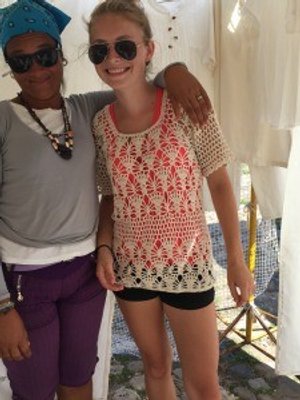 Twee lachende vrouwen, één met blauwe bandana en zonnebril en de ander in een beige gehaakte top, staan arm in arm in Cuba