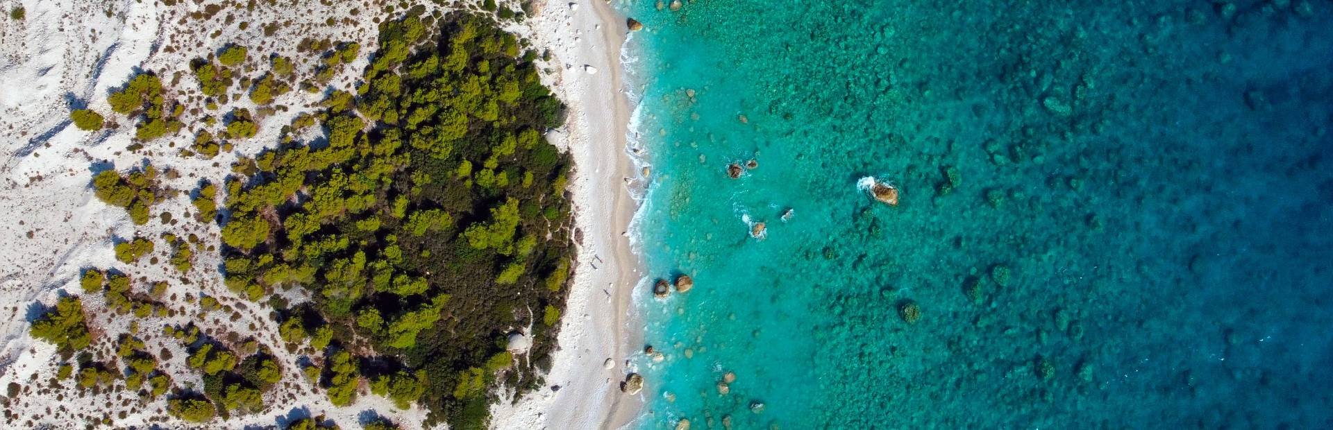 Luchtfoto wit zandstrand tussen turquoise zee en groene kustvegetatie Albanië