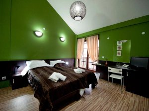 Hotelkamer met twee bedden, groene muren en balkon met gordijnen in Bitola in Noord-Macedonië