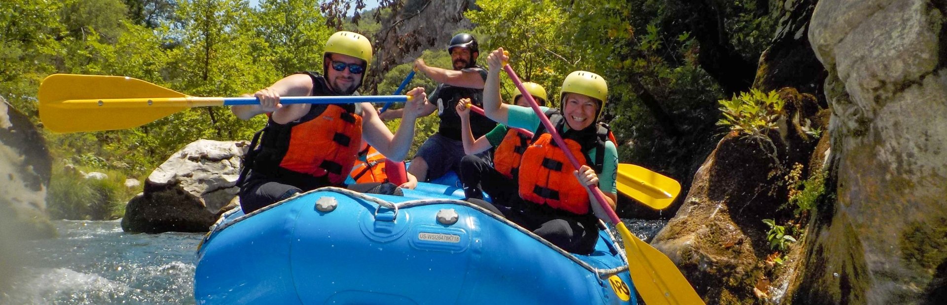 Vier lachende mensen met helmen en reddingsvesten tijdens het wildwaterraften op een rivier in Kroatië