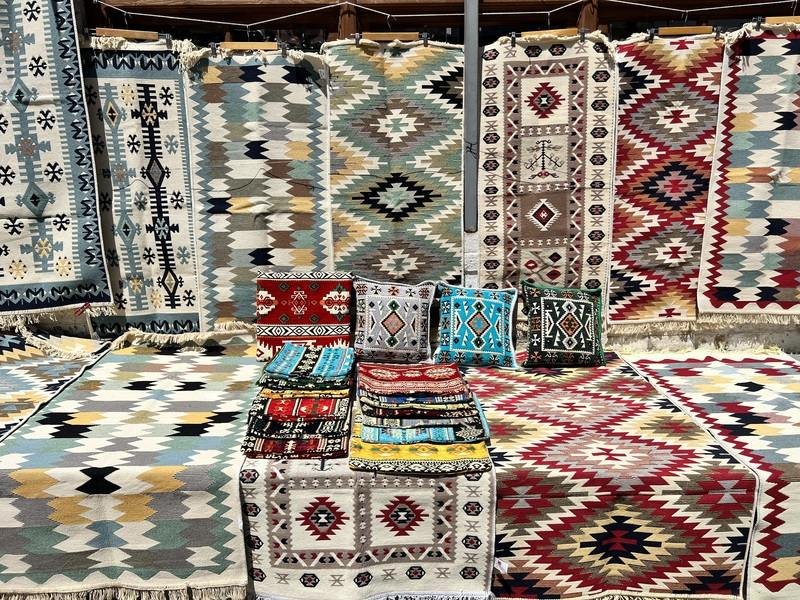 Marktstalletje in Gjirokastër in Albanië met kleurrijke tapijten en kussens met geometrische patronen
