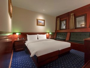 Klassieke hotelkamer met houten inrichting, comfortabel bed en warme verlichting in Skopje in Noord-Macedonië