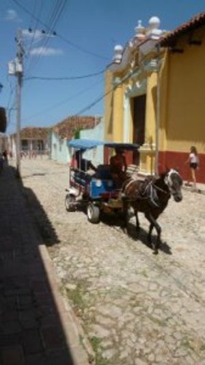 Paard en wagen rijden over een kasseienstraat in een kleurrijke stad bij Trinidad in Cuba