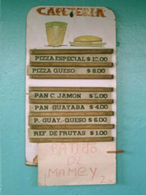 Wit menubord in een cafetaria in Havana, Cuba met handgeschreven Spaanse gerechten en prijzen zoals pizza’s, sandwiches en drankjes, inclusief een mamey milkshake