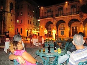 Gezellig verlicht plein in Trinidad, Cuba ’s avonds met mensen aan tafels, een stel op de voorgrond en een band die live muziek speelt