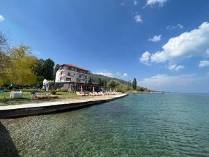 Hotel aan het Ohridmeer in Noord-Macedonië met stoelen aan het heldere water onder een blauwe lucht