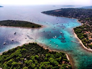 Luchtfoto van een baai met helder blauw water, eilanden, groene kustlijn en veel boten in Dalmatië