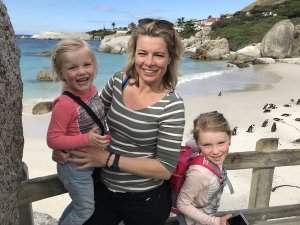 Lachende vrouw met twee kinderen op een strand met pinguïns in Zuid-Afrika