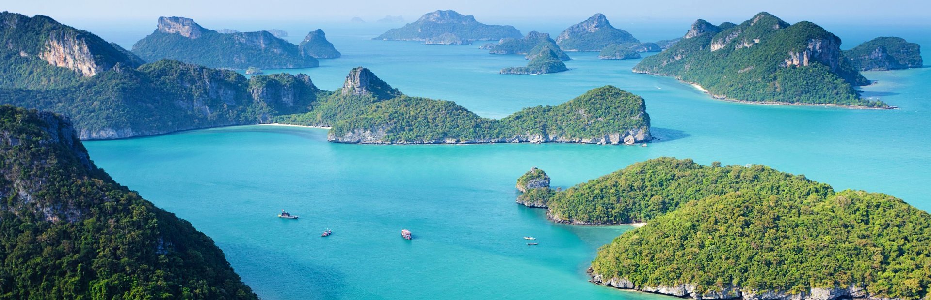 Panoramisch uitzicht op turquoise zee met verspreide, groene kalkstenen eilanden en rotsformaties, gezien vanaf een hoog uitkijkpunt in een tropisch kustgebied.