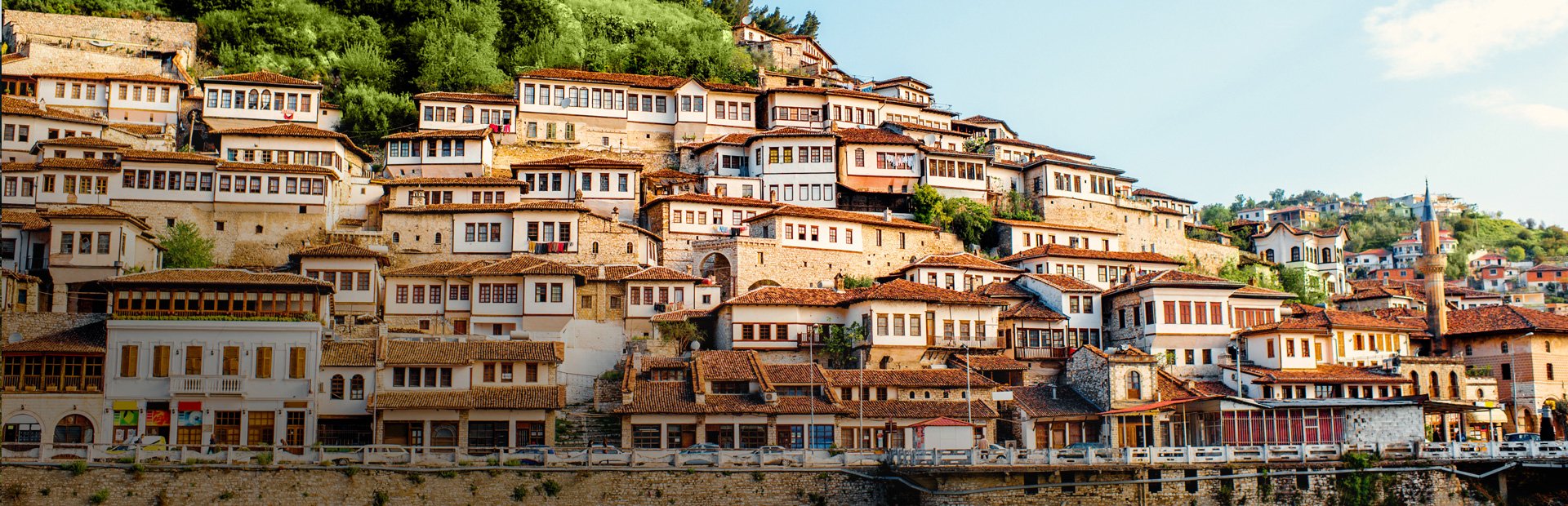 Historische heuvelstad met witte huizen, rode daken en grote ramen op een groene helling in Berat Albanië