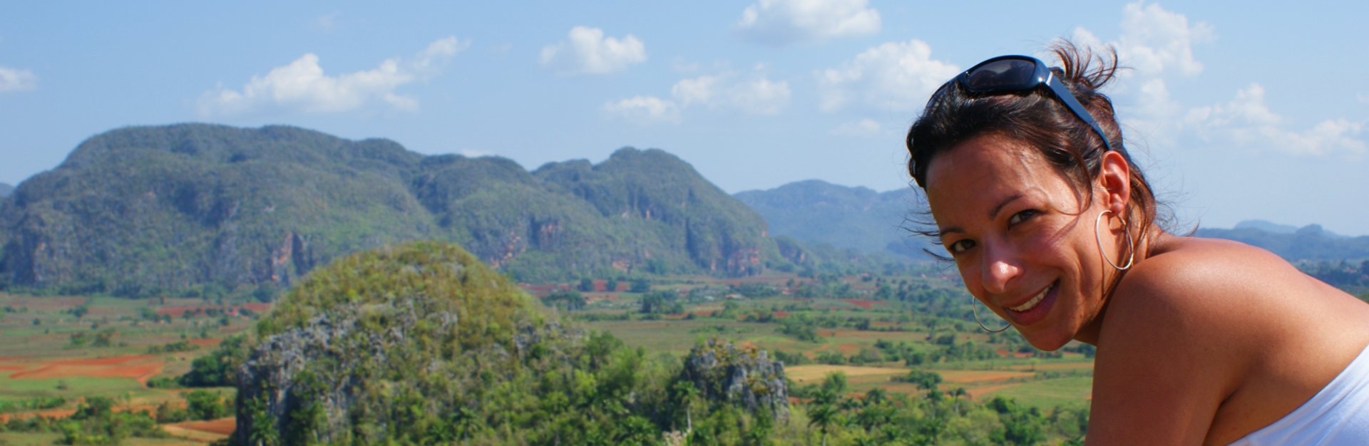 Lachende vrouw met panoramisch uitzicht over groene bergen en velden in Cuba