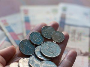 Hand met een handvol munten met onscherpe bankbiljetten op de achtergrond in Cuba