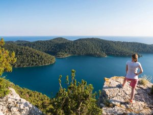 Vrouw op een klif met uitzicht over een baai en beboste eilanden op Mljet