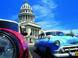 Rode en blauwe vintage auto’s staan voor El Capitolio in Havana in Cuba