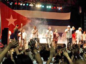 Band treedt op voor een groot Cubaans vlagdecor terwijl publiek met opgeheven handen meedoet in Havana Cuba
